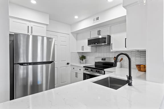 A modern kitchen with a stainless steel refrigerator and a marble countertop.