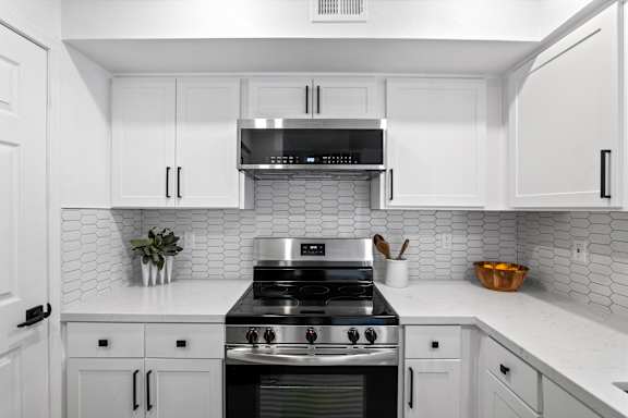 A modern kitchen with a stove top oven and white cabinets.