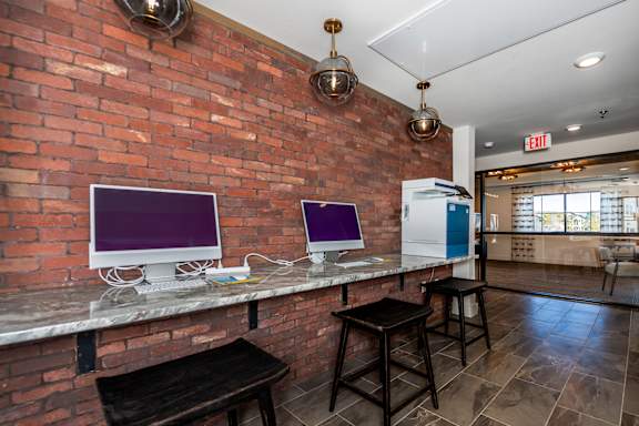 A room with a brick wall and a bar area with two computers on it at The Crossings  at Windsong, Prescott Valley, 86314
