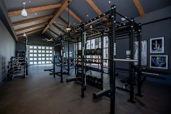 A gym with a variety of equipment including a squat rack, bench, and weights at The Crossings  at Windsong, Prescott Valley, 86314