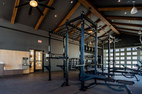 A gym with a variety of equipment including a squat rack, bench press, and a rowing machine at The Crossings  at Windsong, Prescott Valley, 86314