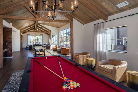 A pool table with a red cloth and a pool cue with a colorful pool ball on it at The Crossings  at Windsong, Prescott Valley, 86314