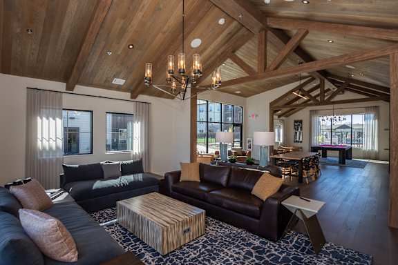 A large, open-concept living room with wooden beams and a variety of seating options at The Crossings  at Windsong, Prescott Valley, 86314