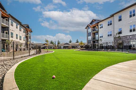 A ball is sitting on a green lawn in front of apartment buildings at The Crossings  at Windsong, Prescott Valley, 86314