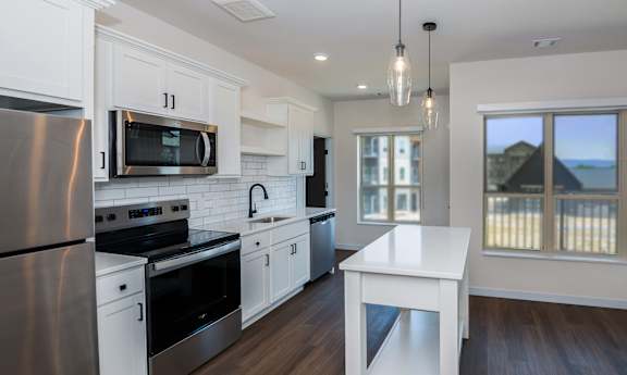 A modern kitchen with white cabinets and stainless steel appliances.