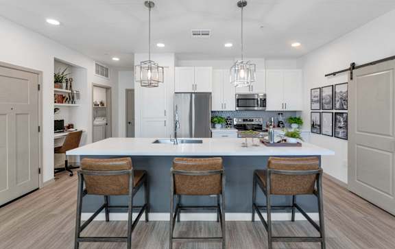 A kitchen with a white countertop and brown barstools.