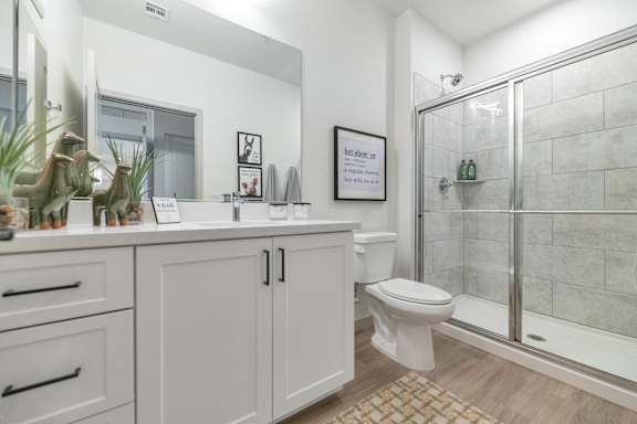 A white bathroom with a toilet, sink, and mirror.