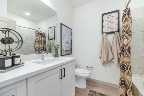 A bathroom with a white toilet, sink, and a framed picture on the wall.