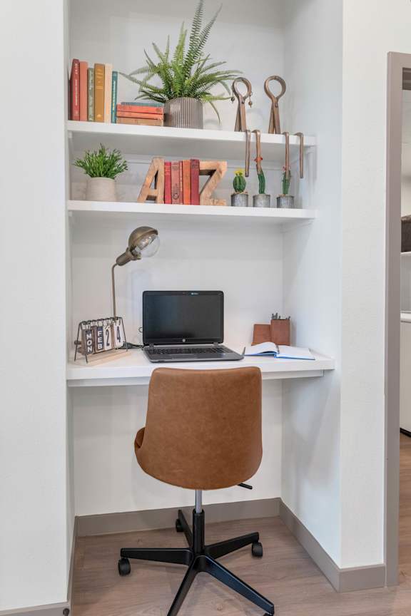 A brown chair is in front of a desk with a laptop on it.