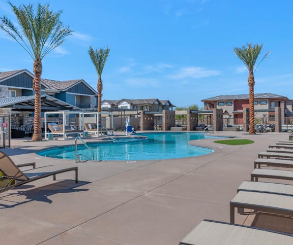 A pool surrounded by palm trees and sun loungers.