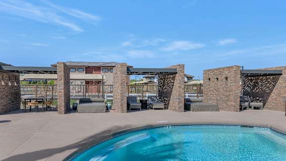 A pool surrounded by stone pillars and a building in the background.