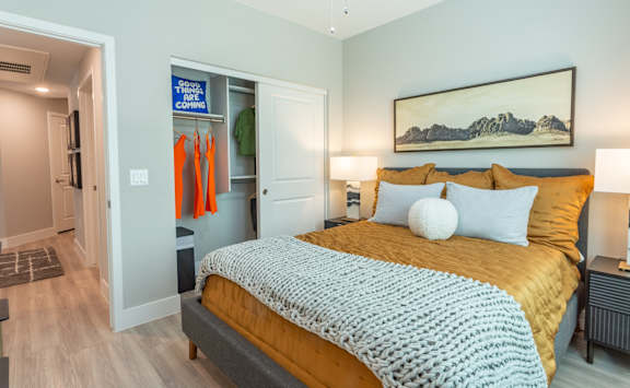 A bedroom with a bed, a nightstand, and a painting on the wall.