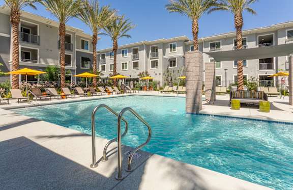 A swimming pool surrounded by palm trees and lounge chairs.