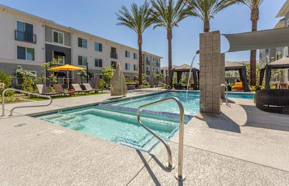 A swimming pool surrounded by palm trees and a building in the background.