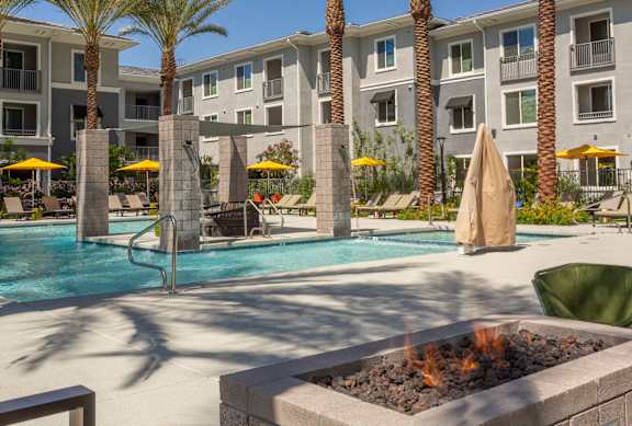 A pool surrounded by palm trees and umbrellas.