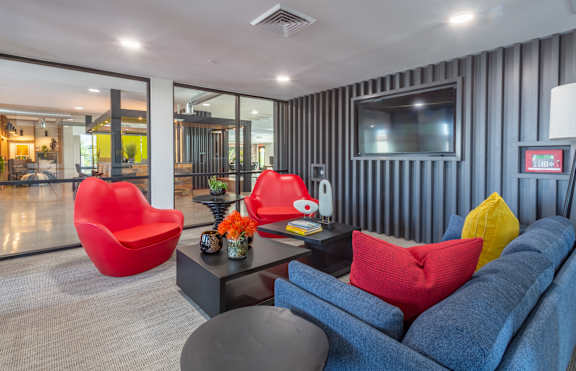 A living room with a blue couch, red chair, and a grey coffee table.