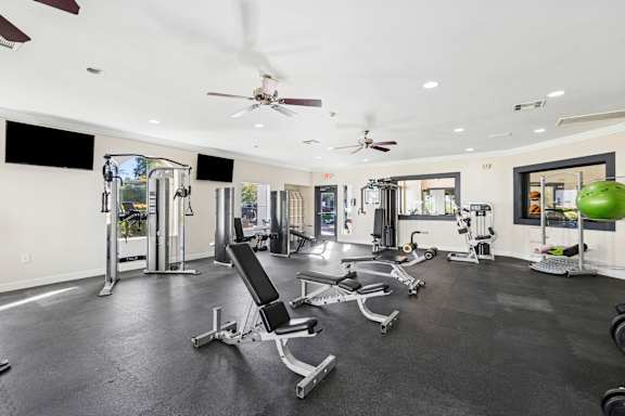 A gym with a variety of equipment including weights and cardio machines.