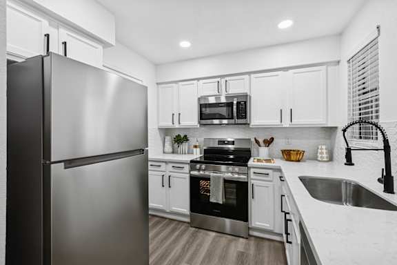 A modern kitchen with a stainless steel refrigerator and white cabinets.