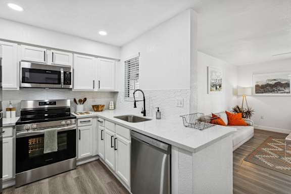 A modern kitchen with white cabinets and stainless steel appliances.