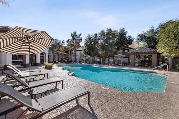 A pool surrounded by lounge chairs and umbrellas.