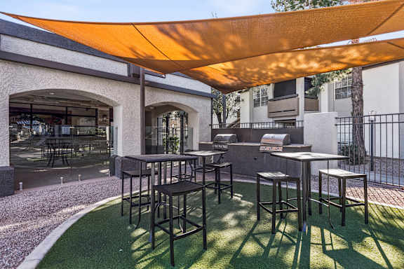 A patio with a table and chairs under a shade sail.
