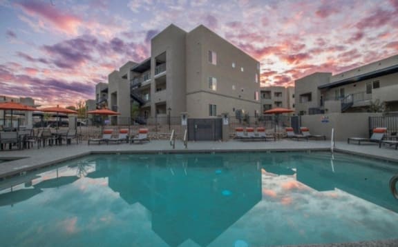 a swimming pool at sunset with a building in the background
