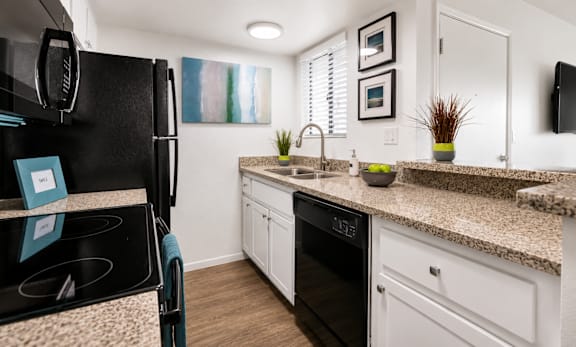 A kitchen with a black fridge and white cabinets.