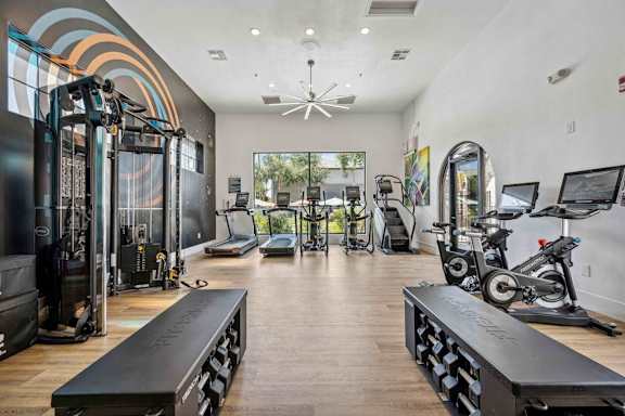 A gym with a variety of equipment including treadmills, weights, and exercise bikes. at Lazo Apartment Homes, Chandler, AZ