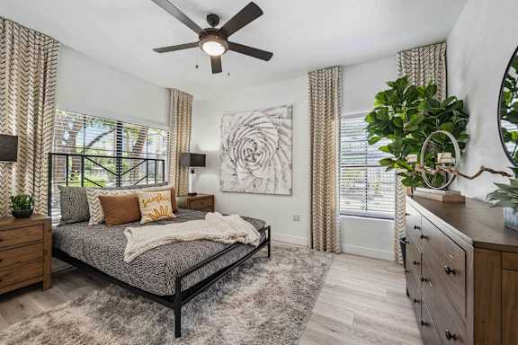 A bedroom with a bed, dresser, and ceiling fan. at Lazo Apartment Homes, Arizona