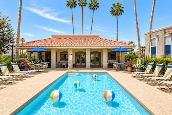 A pool with a house and palm trees in the background.