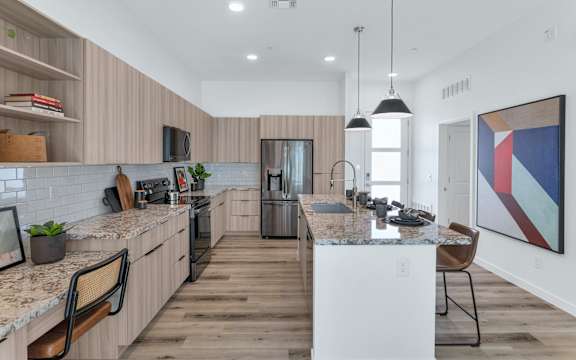 A modern kitchen with wooden floors and a marble countertop.at Marketside Villas at Verrado, Buckeye Arizona