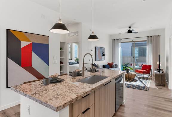 A modern kitchen with a granite countertop and a large abstract painting above it.at Marketside Villas at Verrado, Buckeye, AZ