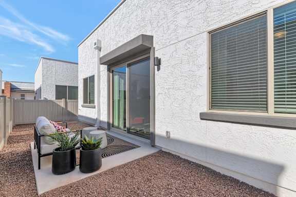 A white house with a patio and a chair.at Marketside Villas at Verrado, Buckeye, 85396