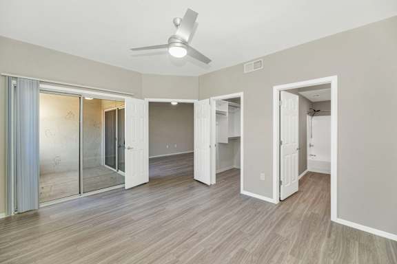 an empty living room with a ceiling fan and a mirrored closet