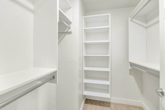 a walk in closet with white shelves and a white closet door