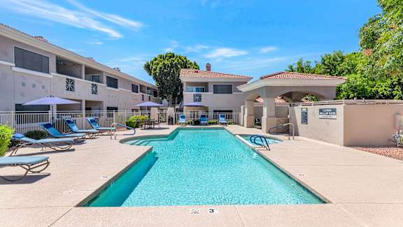 a swimming pool with lounge chairs and a building in the background