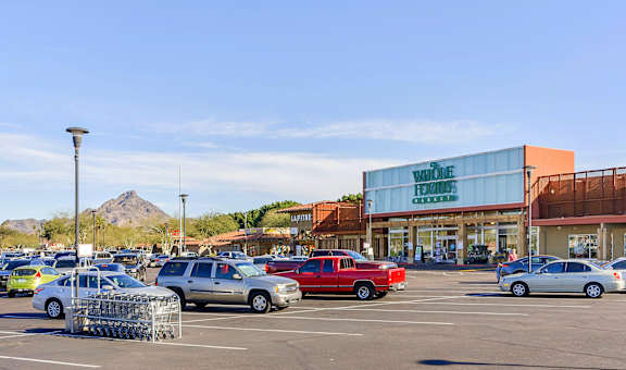 a parking lot filled with cars in front of a shopping center