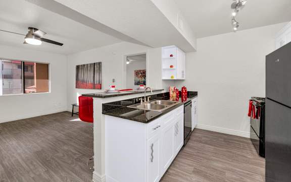 A kitchen with white cabinets and a black countertop at Urban WalkApartments on 6th Avenue, Phoenix, AZ