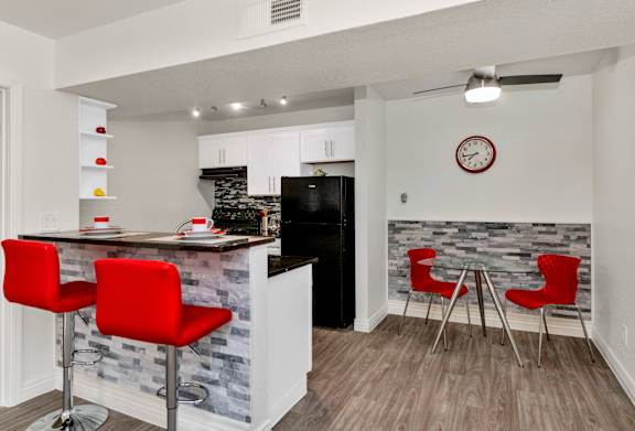 A kitchen with a bar area and red chairs at Urban WalkApartments on 6th Avenue, Phoenix