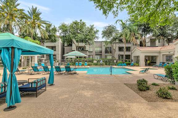 A pool area with a blue canopy and lounge chairs.