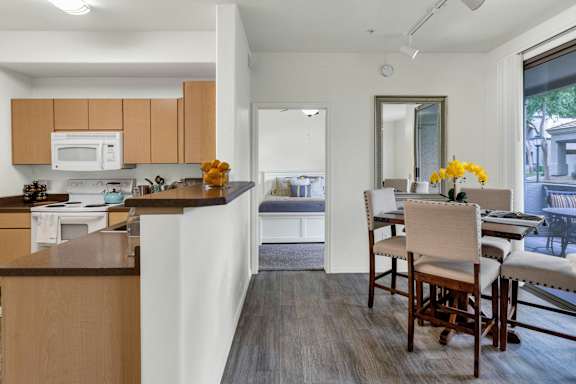 A kitchen with wooden cabinets and a dining table with chairs.