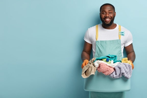 a man wearing an apron holding a pile of laundry