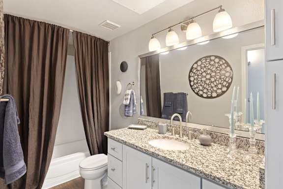 A bathroom with brown curtains and a round mirror.