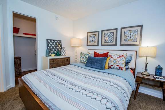 A bedroom with a large bed and a dresser with a mirror.