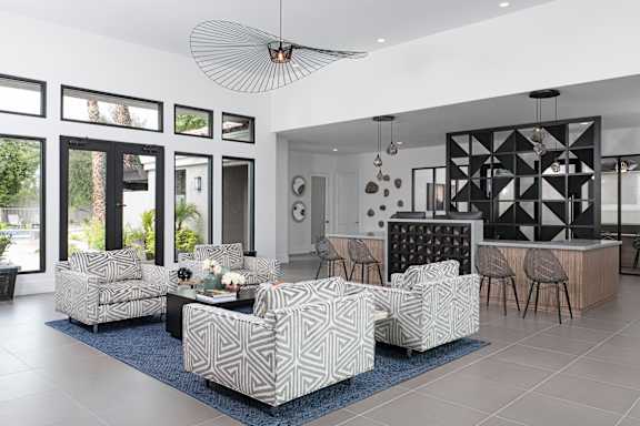 A modern living room with a patterned sofa set and a black geometric wall art.