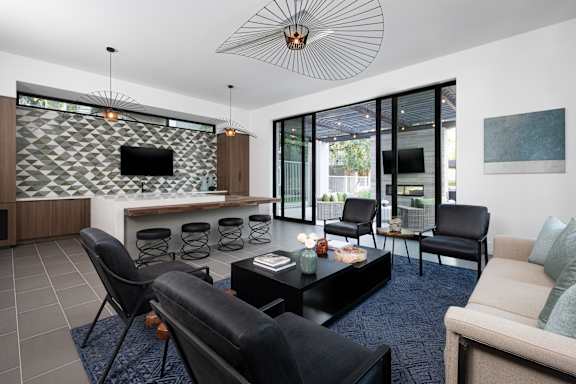 A modern living room with black leather chairs and a patterned wall.