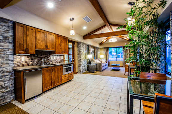 A kitchen with wooden cabinets and a stone wall.