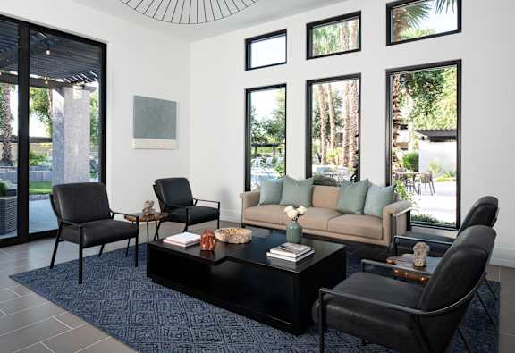 A living room with a black coffee table and a couch with green pillows.