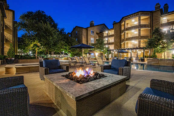 A fire pit in the middle of a patio surrounded by chairs.