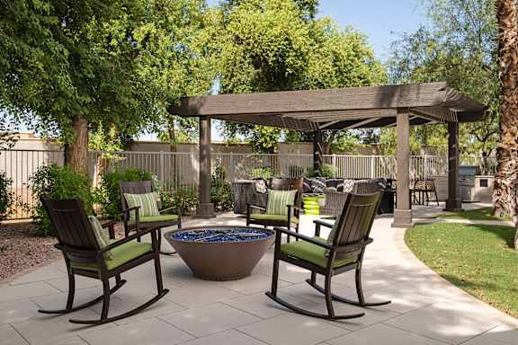 A patio with a fire pit and chairs.
